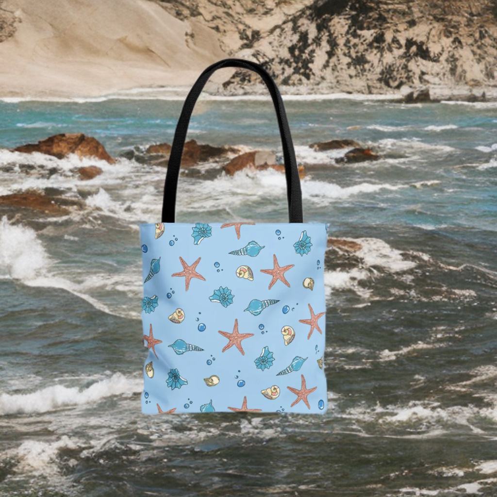Beach tote bag with shell and starfish design on a seaside backdrop.