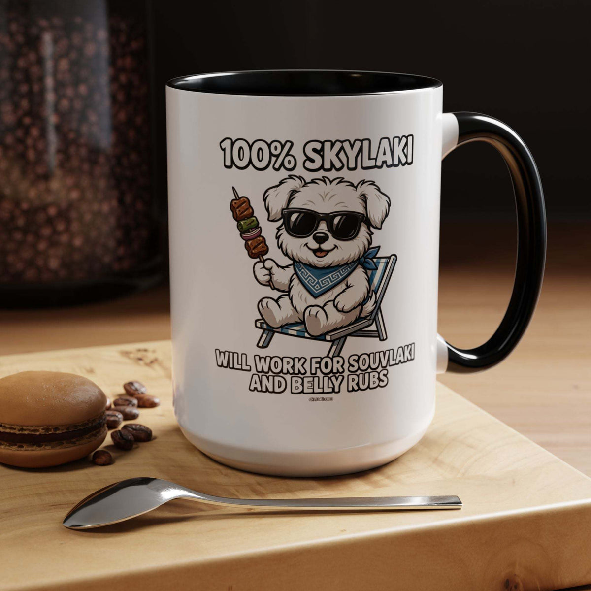 Coffee mug with a white ceramic exterior, black interior and handle, showing a sunglass-wearing dog and “Will Work for Souvlaki and Belly Rubs” text