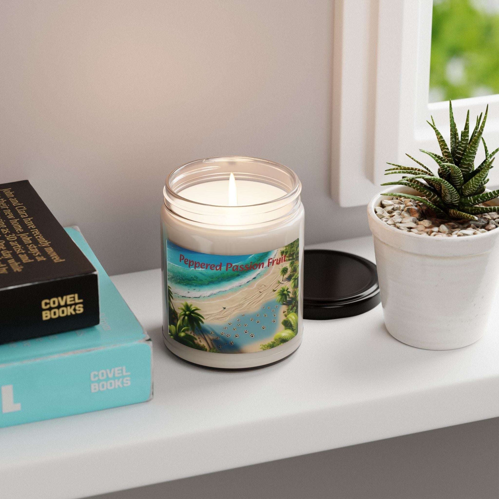 Tropical Paradise Scented Soy Candle - 9oz with beach-themed label on a table next to books and a potted plant.