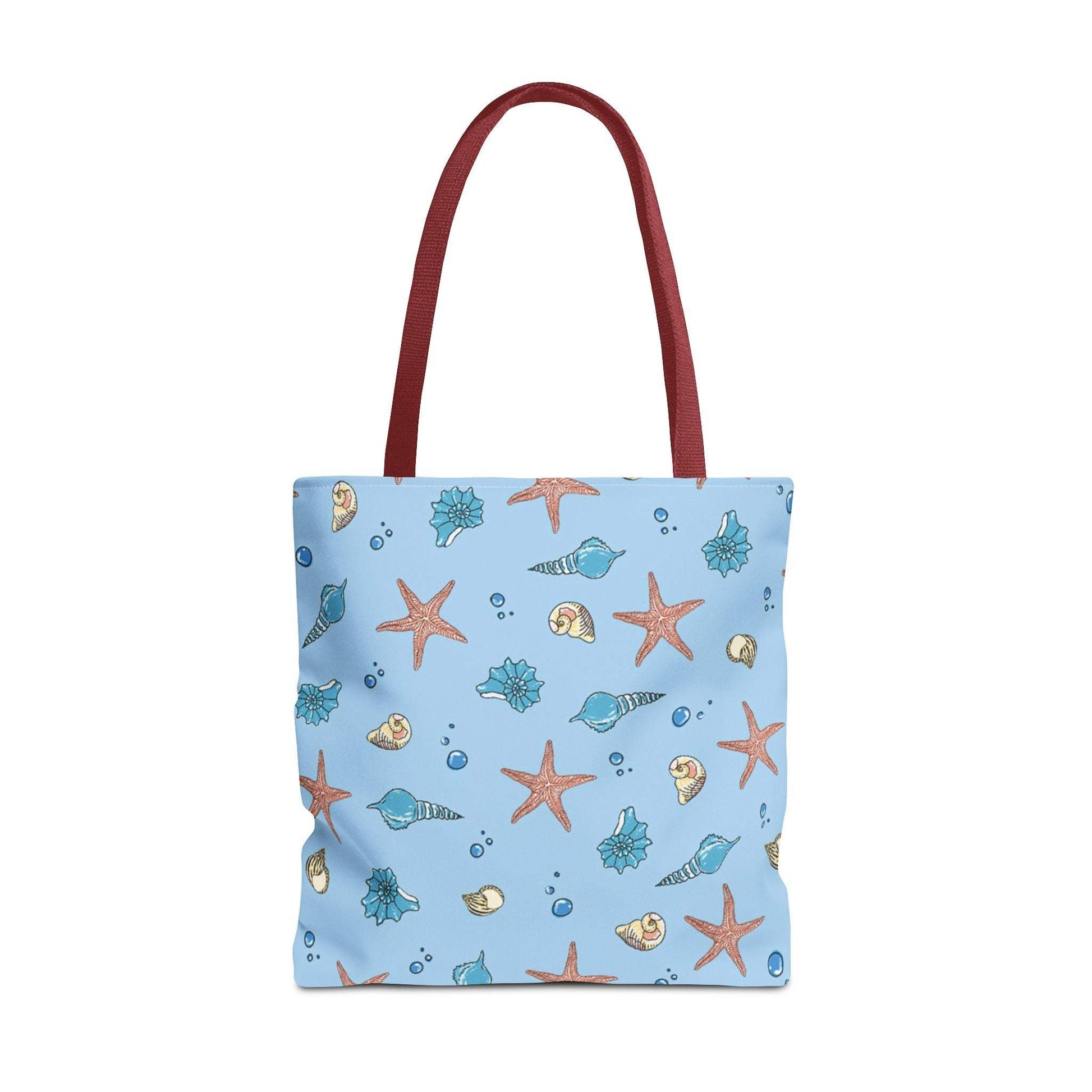Beach tote bag with shell and starfish design, featuring a blue ocean-themed pattern and red handles.