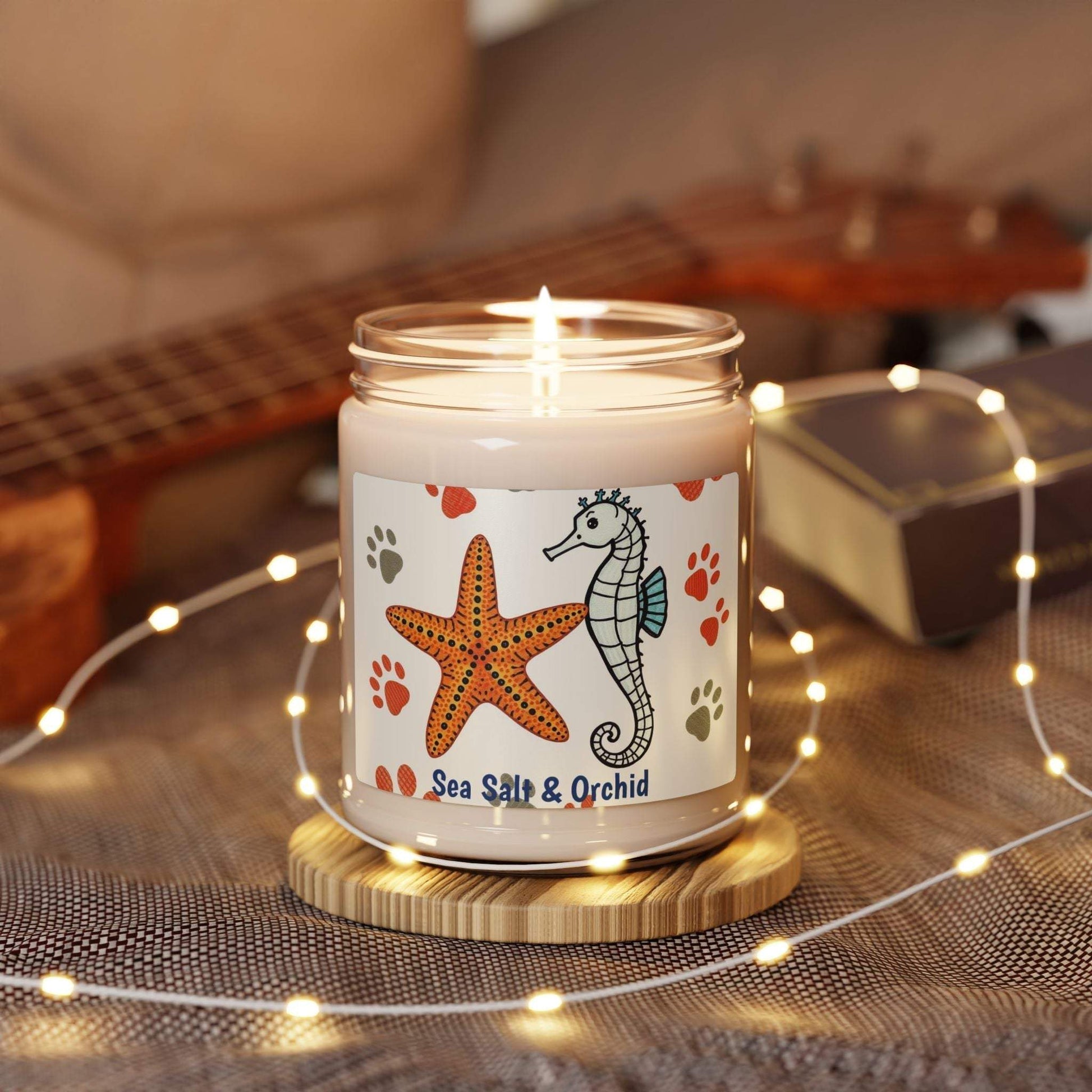 Scented soy candle with sea salt and orchid scent, featuring a decorative seahorse and starfish design, set on a cozy table with fairy lights.