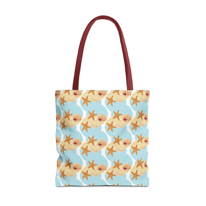 Seashell and starfish beach tote bag with coastal pattern and red handles.