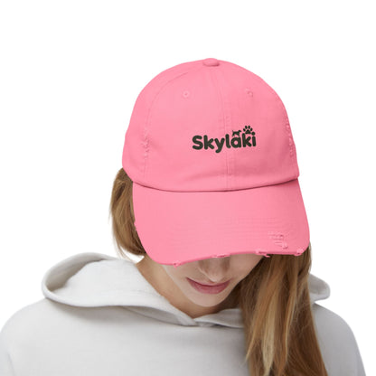 Unisex distressed cap with Skylaki logo, pink cotton twill, curved visor, eyelets, and adjustable strap.
