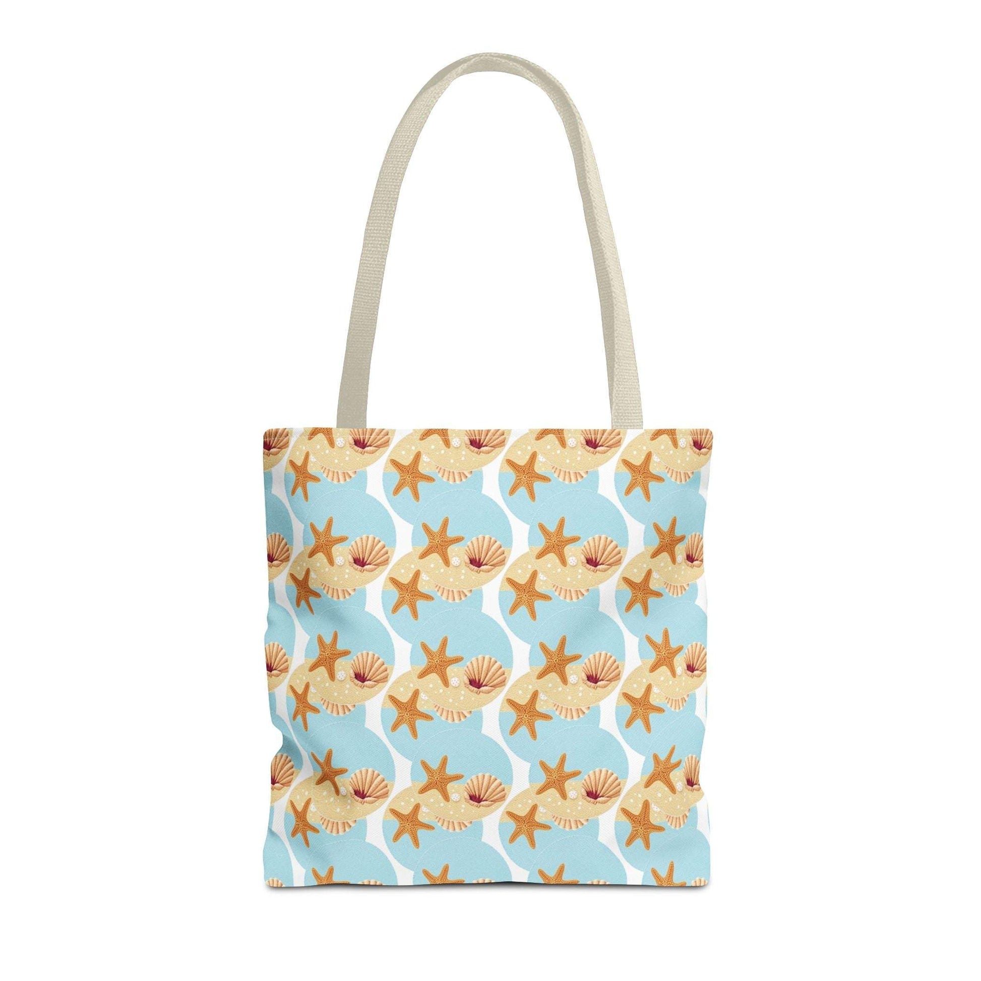Seashell and starfish beach tote bag with coastal pattern on a blue background, featuring beige handles.