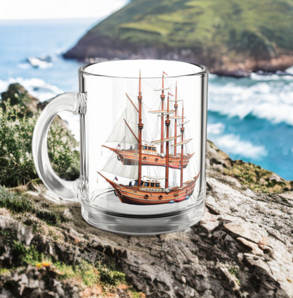Nautical glass mug with tall ship design on coastal background.
